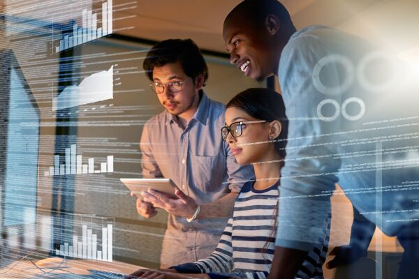 This image shows three computer programmers working through data in the office 