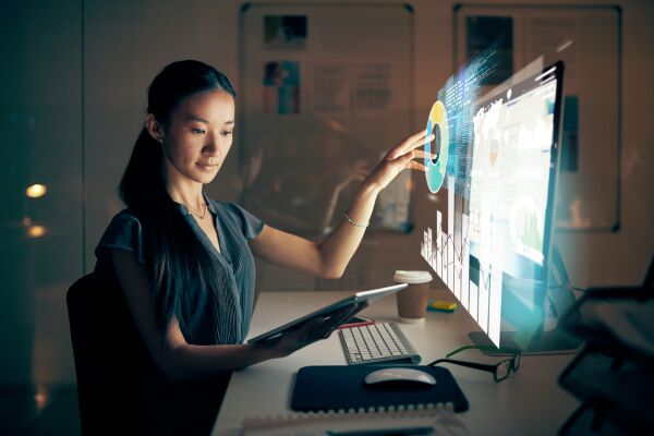 This image shows a programmer using a digital tablet and desktop computer in a modern office.