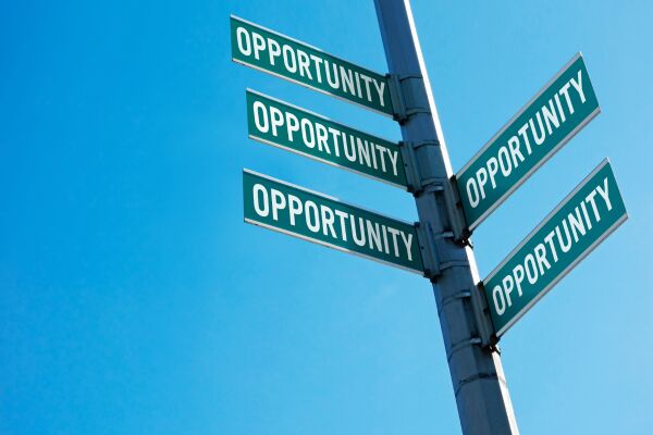 Metal pole with multiple green signs saying ‘opportunity’ with blue sky background