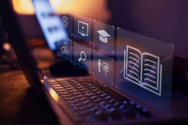 Laptop with icons showing a book, a graduation cap, a screen, a person, a search icon