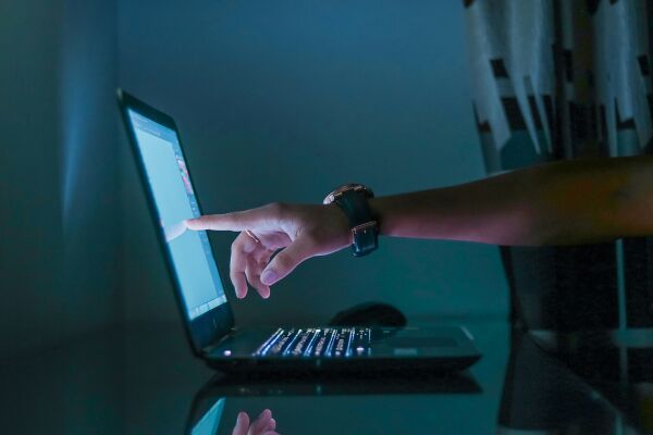 Human interacting with laptop on table