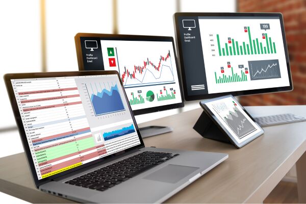 Three computer screens showing data graphics.