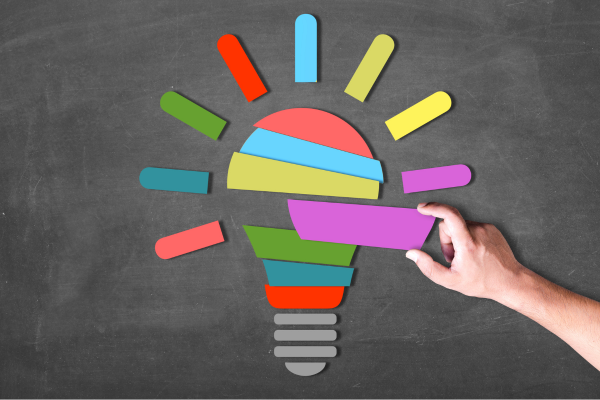 Multi-coloured graphic of a lightbulb with a human hand.