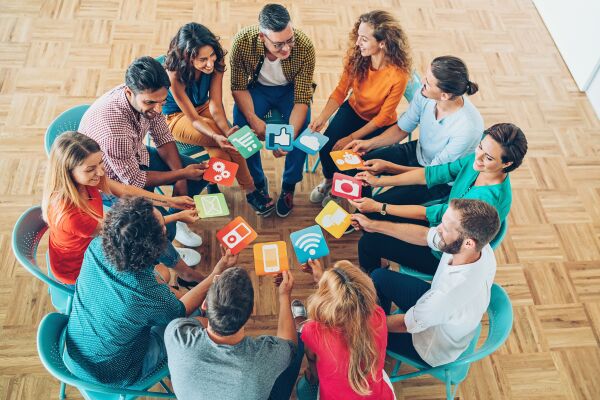 People sitting in a circle on chairs with social media icons in hands