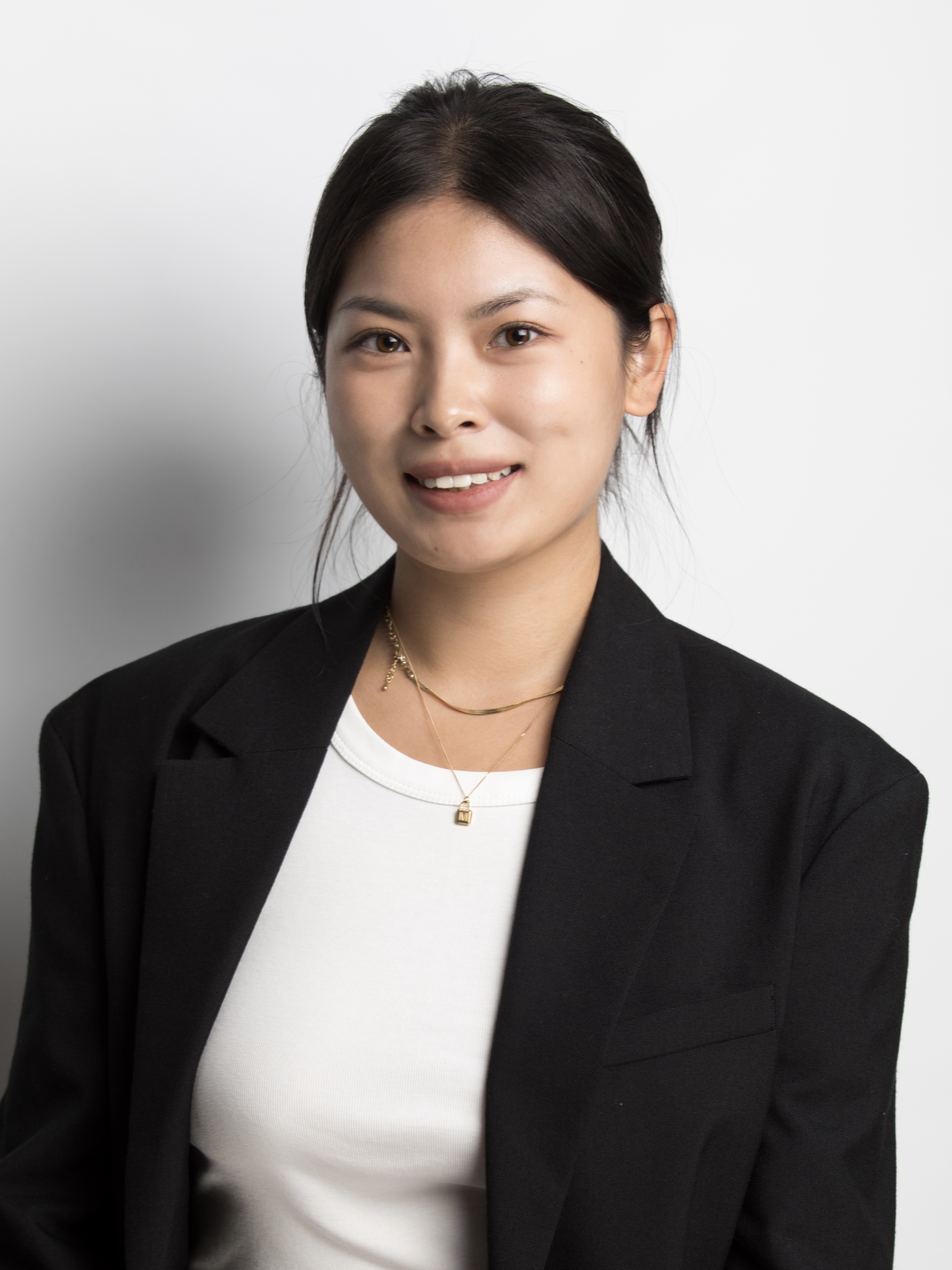Headshot of Yumeng in a black suit jacket and white shirt. She is smiling.
