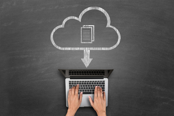 A cloud with a document inside, pointing downwards towards a person typing on a computer