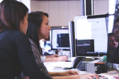 Two Women Sitting in Front of Computer Monitor